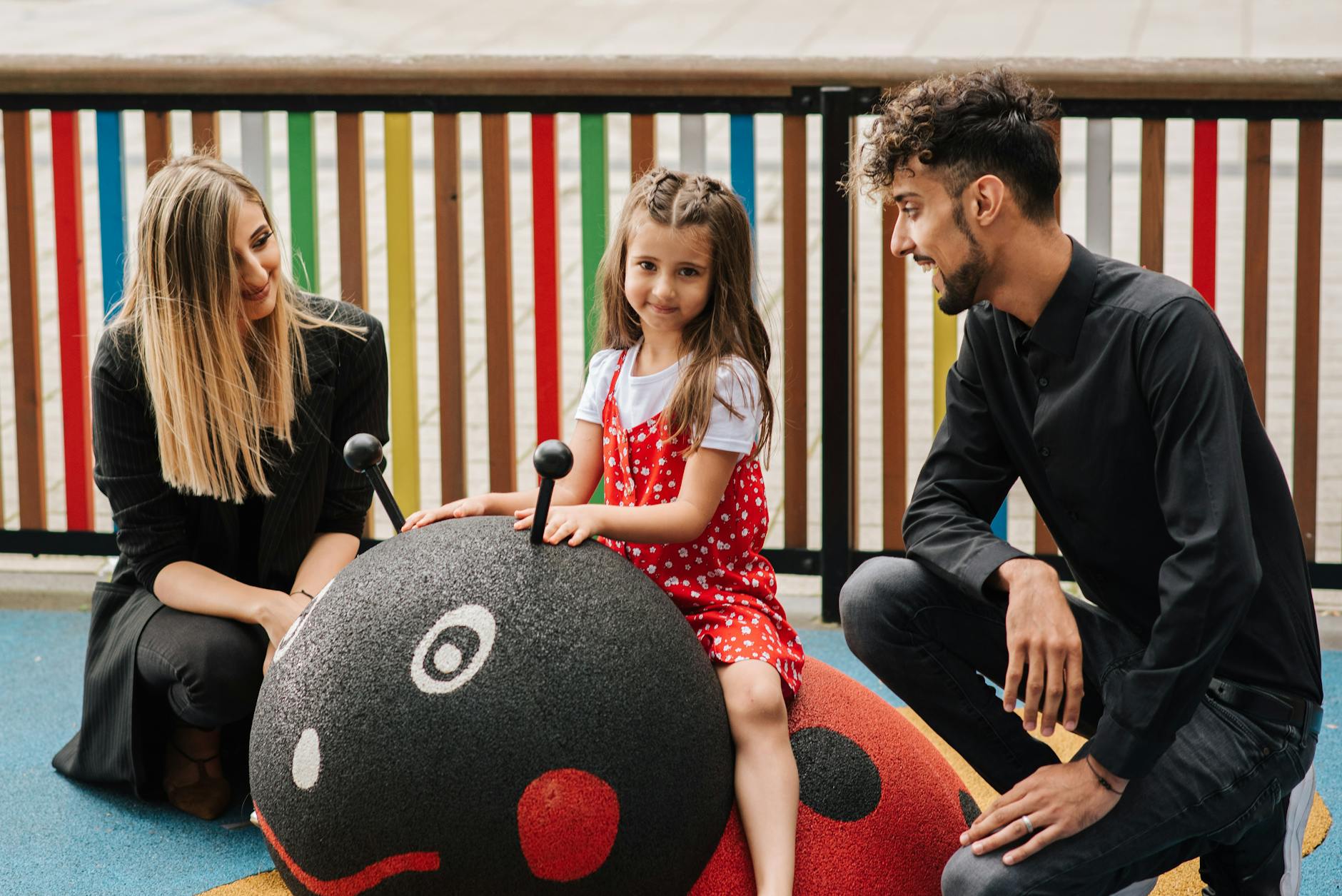 Rodzice z dzieckiem bawią się na biedronkowej huśtawce w parku