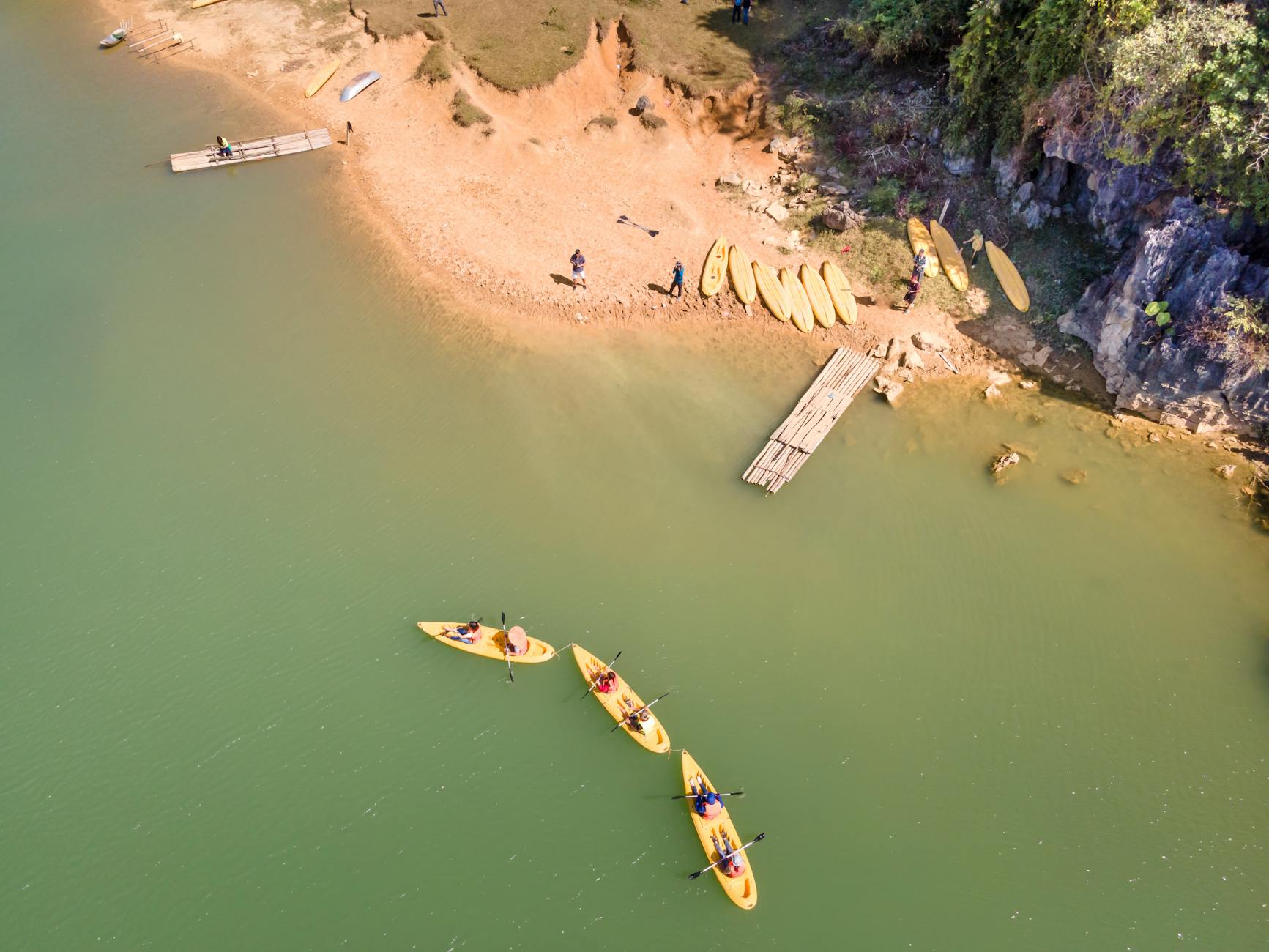 Kajakarze płynący po spokojnym jeziorze obok piaszczystej plaży