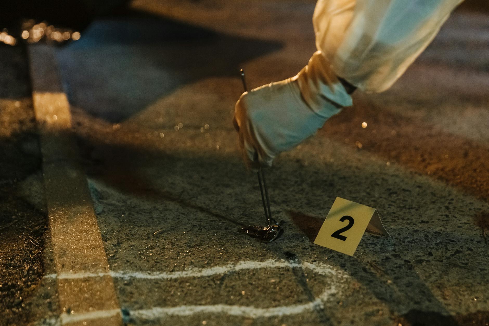 Technik kryminalistyki w rękawiczkach zabezpiecza dowód nocą