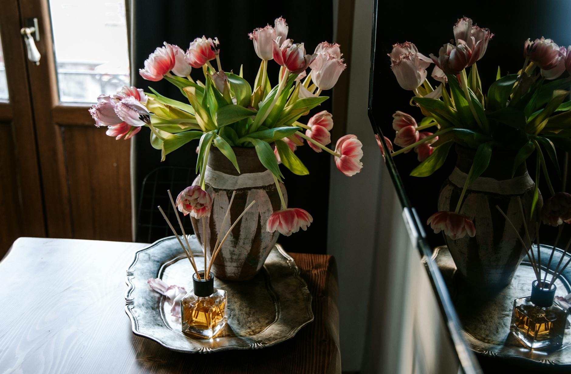 Domowe aromaty w stylu eko: jak wybierać zapachy do wnętrz, które są bezpieczne dla zdrowia Tulipany w wazonie i dyfuzor zapachowy na tacy w domowym wnętrzu